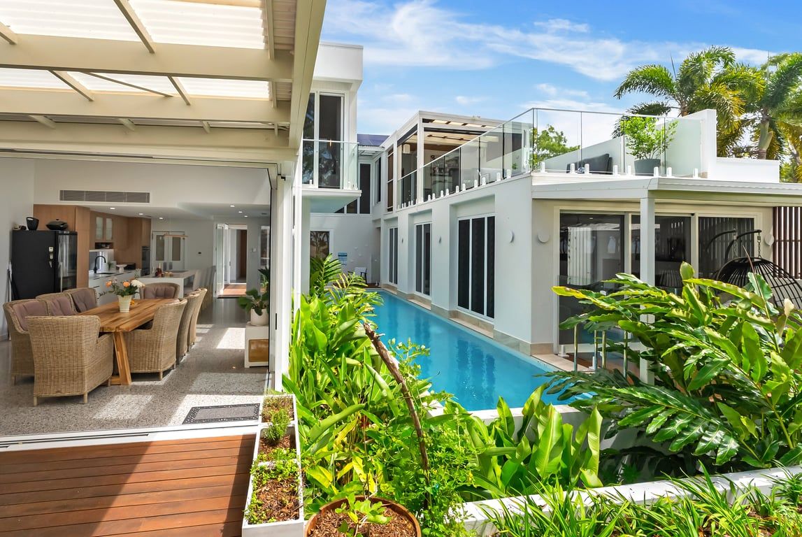 A modern residential property with a swimming pool, outdoor seating area, and lush greenery.