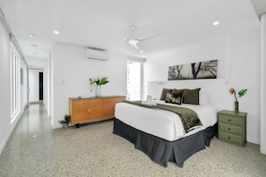 A bedroom with a bed, a dresser, a nightstand, a ceiling fan, and a window. - Belle Escapes Beach Villa San Remo (Holloways Beach)