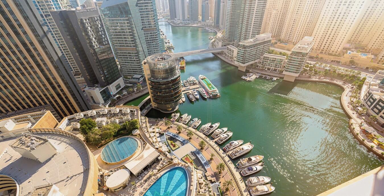 Ein Hochhotel mit einer Marina, mehreren Schwimmbecken und einer Brücke zu anderen Gebäuden.