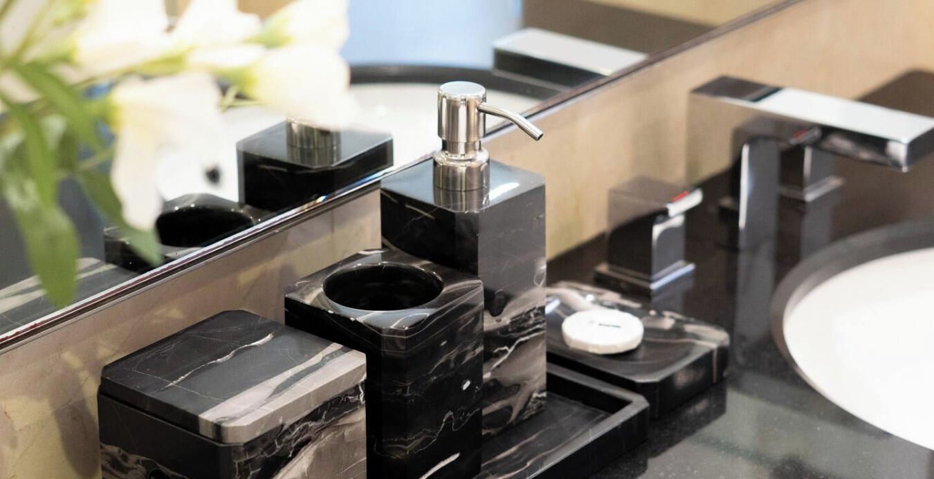 Ein modernes Badezimmer mit einem schwarzen Marmorwaschbecken, einem weißen Seifenspender und einem Chromarmaturen.