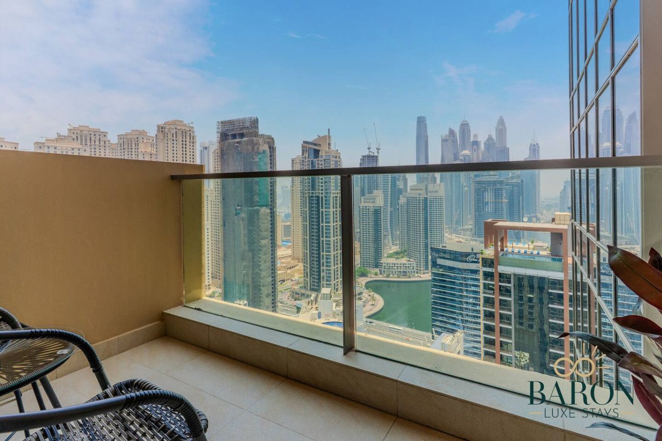 Un balcón con vista a la ciudad, una silla y un letrero que dice 'BARON LUXE STAYS'.