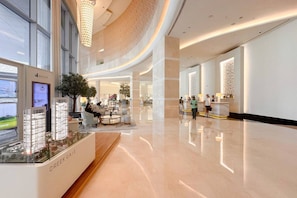 A spacious hotel lobby with a modern design, featuring a reception desk, seating areas, and a large window overlooking the street. - The Glamorous • JW Marriott (Dubai)
