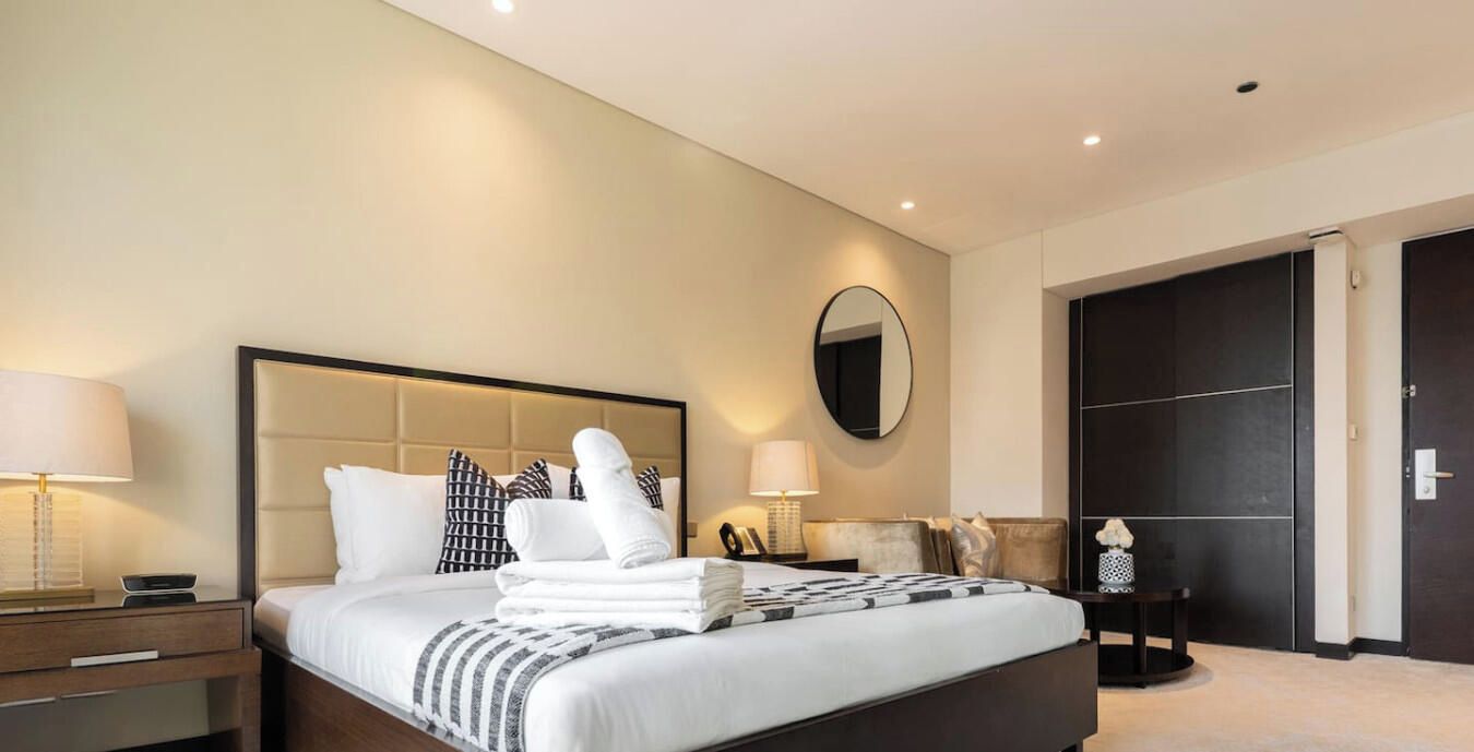 Een hotelkamer met een bed, nachtkastjes, een spiegel en een kledingkast.