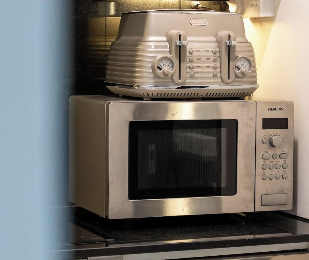 A stainless steel microwave oven with a digital display and control panel, placed on a kitchen countertop.