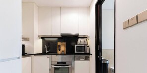 A compact kitchen with a microwave, oven, and a coffee machine. - The Serene • JW Marriott (Dubai)