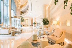 Eine geräumige Lobby mit hoher Decke, mehreren Sitzbereichen und großen Fenstern für viel Tageslicht.