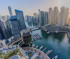 A high-rise urban area with modern architecture, a marina with boats, and a curved waterway. - The Prestige • JW Marriott (Dubai)