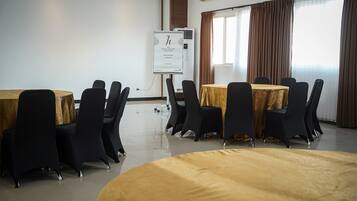 A conference room with round tables, black chairs, a whiteboard, and an air conditioning unit.