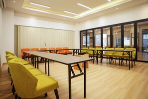 A conference room with a long table and multiple chairs, large windows, and a view of the outside. - Horison Inn Artha Kencana Makassar Hotel (Makassar)