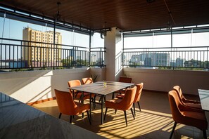 A rooftop terrace with a table and chairs, a view of the cityscape, and a wooden ceiling. - Horison Inn Artha Kencana Makassar Hotel (Makassar)