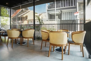Un restaurante con terraza amoblada con sillas de mimbre y mesas redondas.