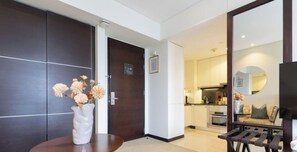 A modern hotel lobby with a dark wood door, a round table with a vase of flowers, and a seating area with a bench. - The Classy • JW Marriott (Dubai)