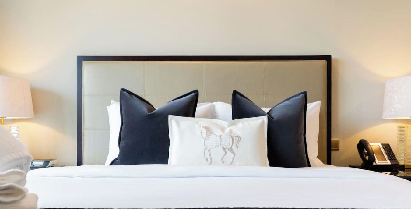 Quarto de hotel com cama, cabeceira e mesa de cabeceira com telefone.
