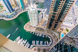 A high-rise building with a marina and boats docked in front. - The Chic • JW Marriott (Dubai)