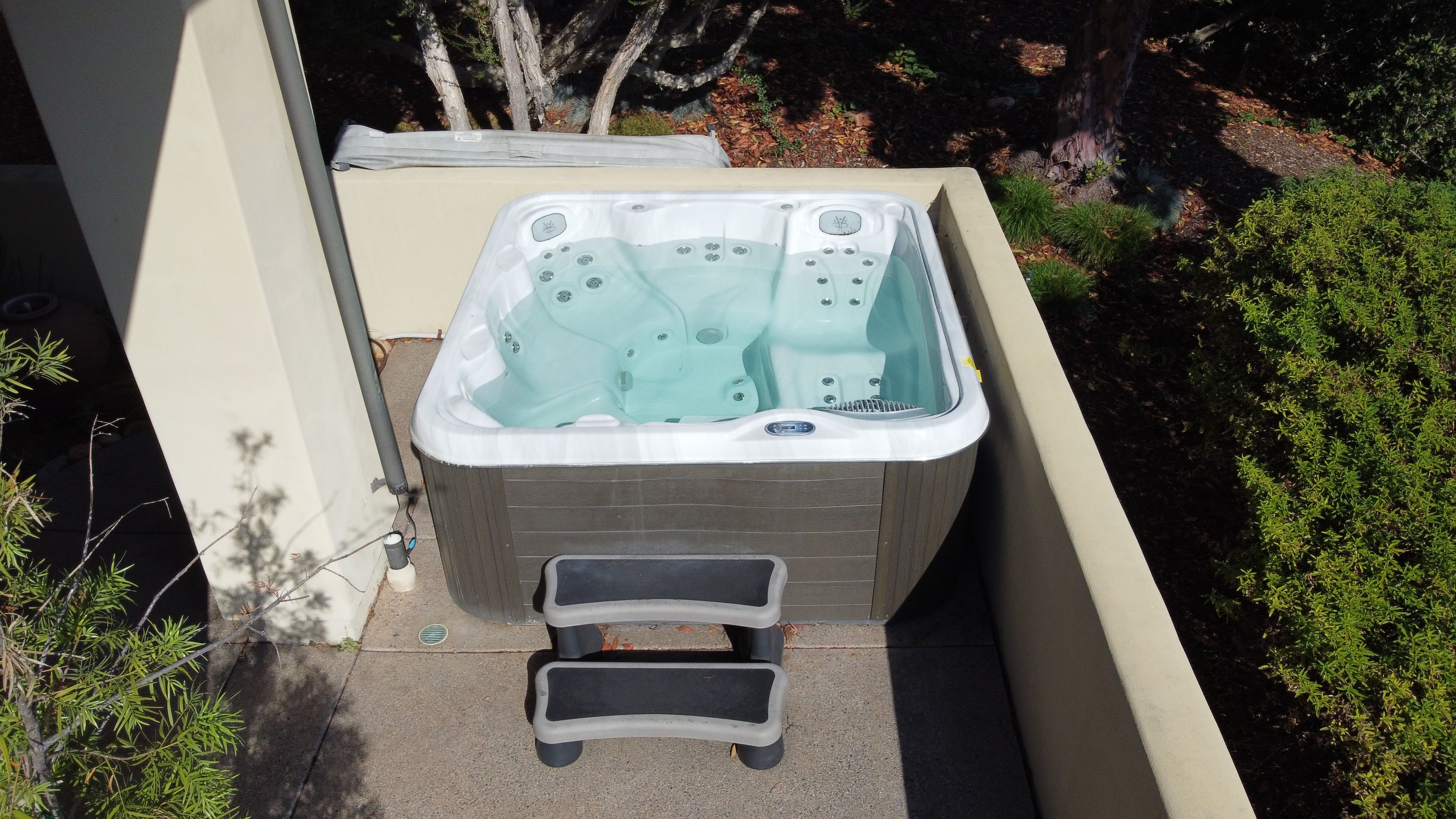 Un bain à remous doté d’un panneau de commande, d’un petit escalier permettant d’y accéder et d’une petite fenêtre.