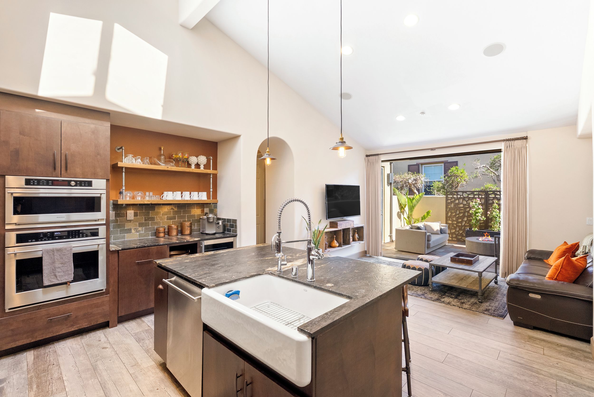A modern kitchen with built-in appliances, a central island, and a dining area with a sofa and table.