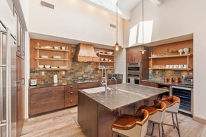 Een moderne keuken met een centraal eiland, barstoelen en ingebouwde apparatuur.