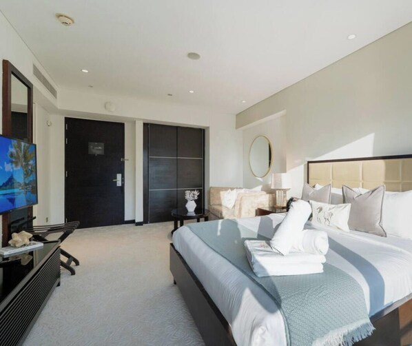 Ein Hotelzimmer mit Bett, Fernseher, Schreibtisch und einer Tür, die auf einen Balkon führt.