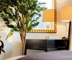 Una habitación con un escritorio, una lámpara, un espejo y una planta en maceta.