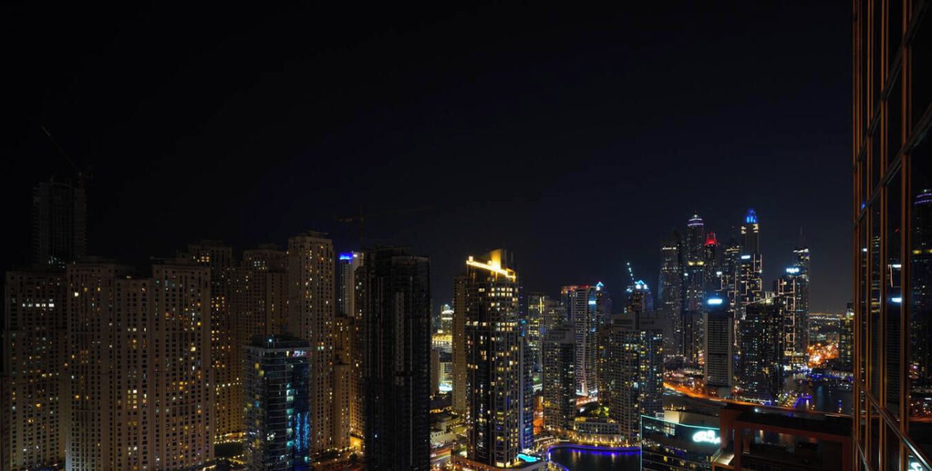 A nighttime cityscape with high-rise buildings and illuminated windows.