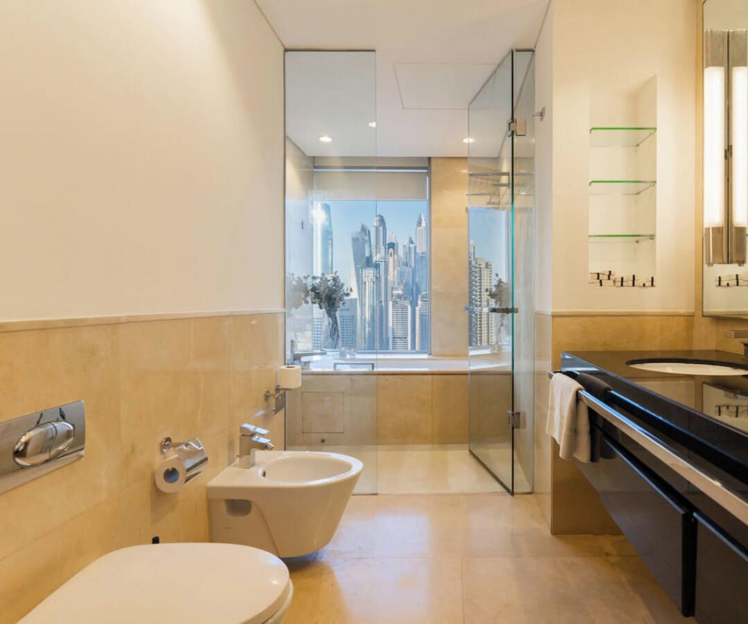 Een moderne badkamer met een bidet, toilet en een grote spiegel.