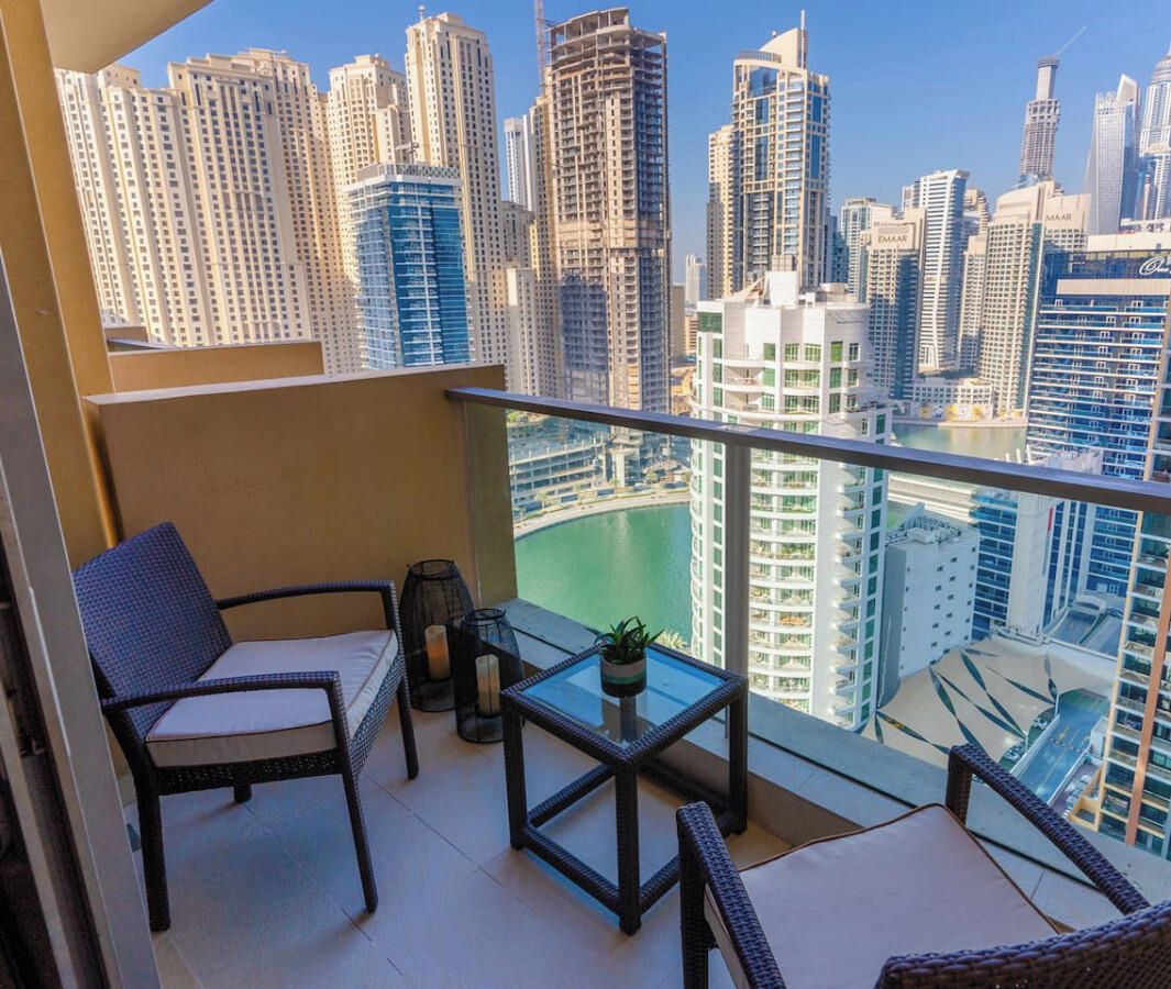 A balcony with a view of a cityscape, including high-rise buildings and a body of water.