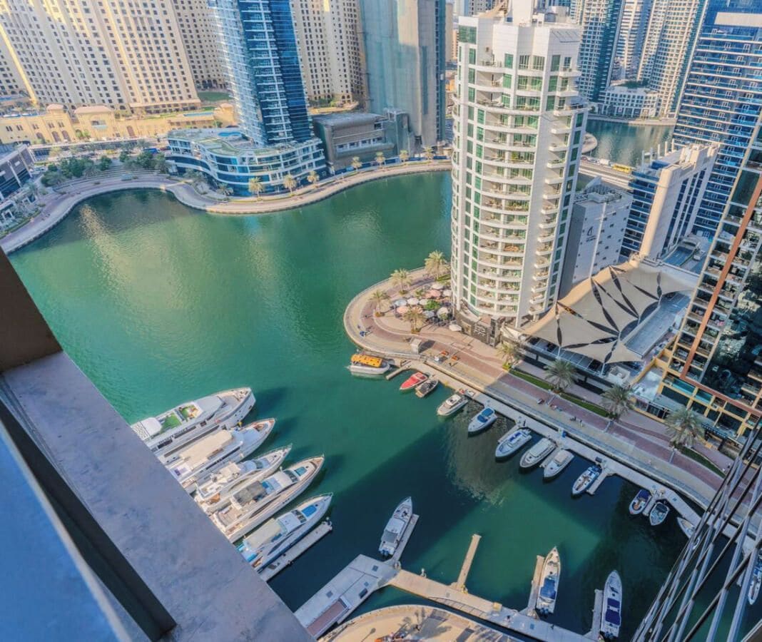 Marina com barcos atracados, cercada por edifícios altos.