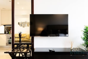 Ein modernes Wohnzimmer mit einem Flachbildfernseher an der Wand, einem Holztisch und einer Couch.