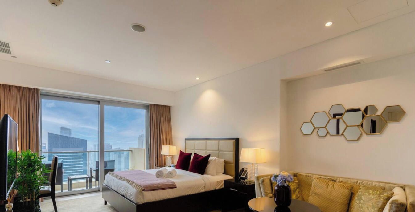 Ein Hotelzimmer mit Bett, einer Sitzecke, einem Fernseher und Blick auf die Stadt.