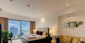 Ein Hotelzimmer mit Bett, einer Sitzecke, einem Fernseher und Blick auf die Stadt.