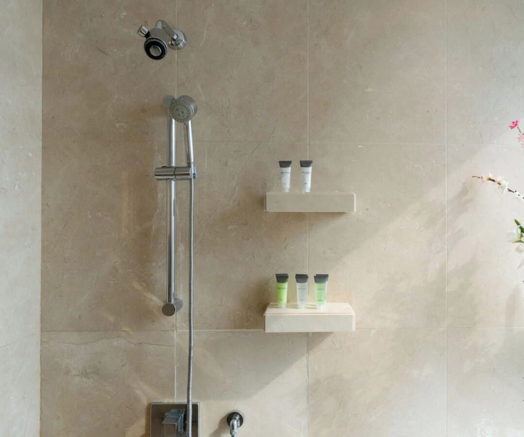 Un bagno con doccia, due ripiani con articoli da toilette e un portasciugamani.