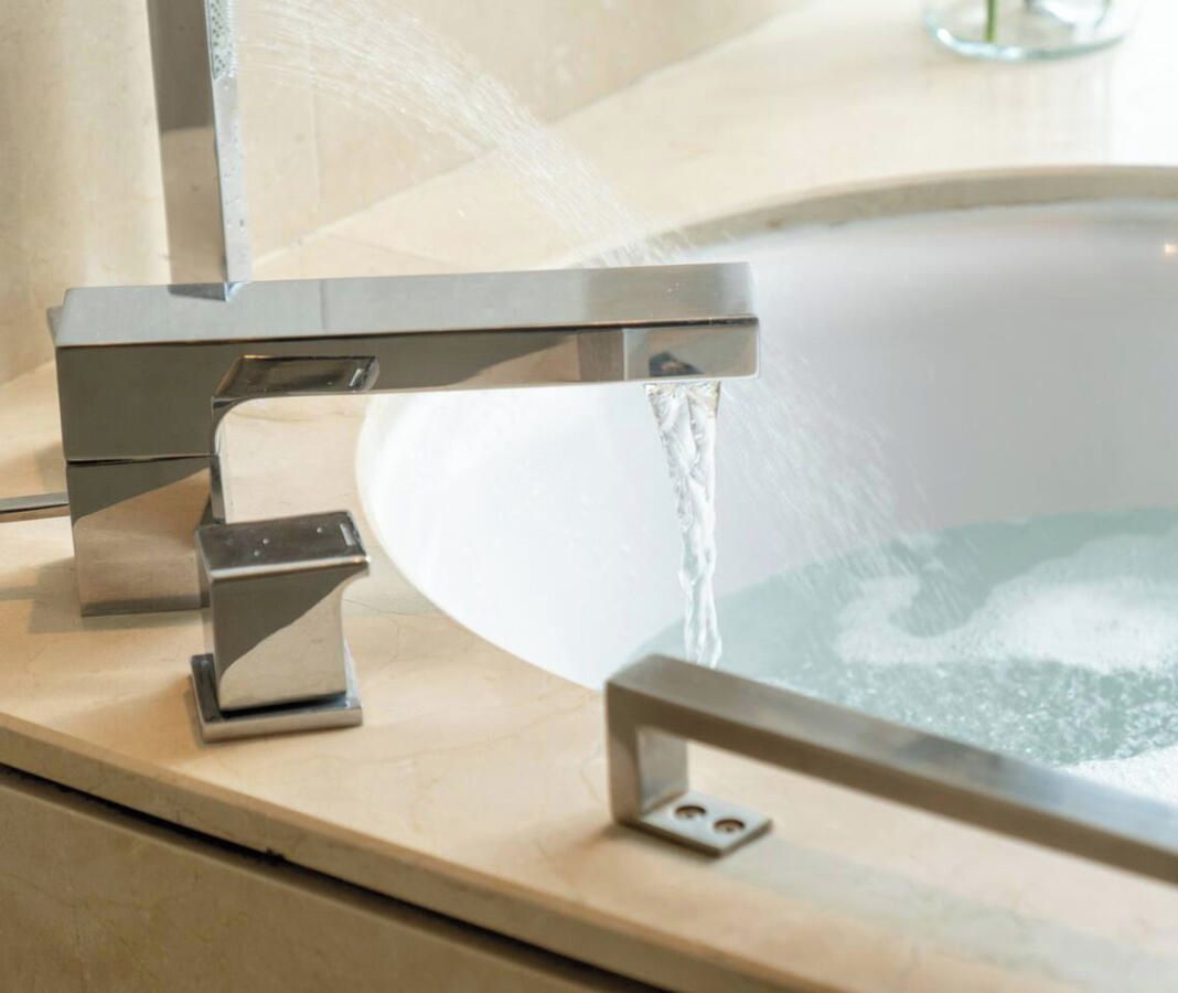 Une salle de bain moderne avec un robinet chromé et une baignoire.