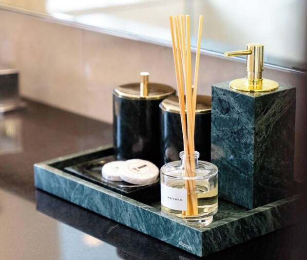 A tray with a diffuser, candles, and reed diffusers on a marble countertop. - The Regal • JW Marriott (Dubai)