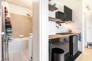 A compact kitchen with a sink, stove, and a trash bin. - Bright Studio-15 Minutes from the Arc de Triomphe (Paris)