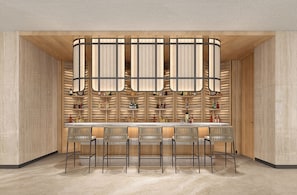 A modern bar area with a wooden bar counter and multiple seating options.