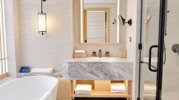 A modern bathroom with a marble vanity, a glass shower enclosure, and a bathtub.
