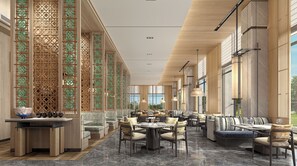 A spacious hotel lobby with a long reception desk, seating areas, and large windows offering views.