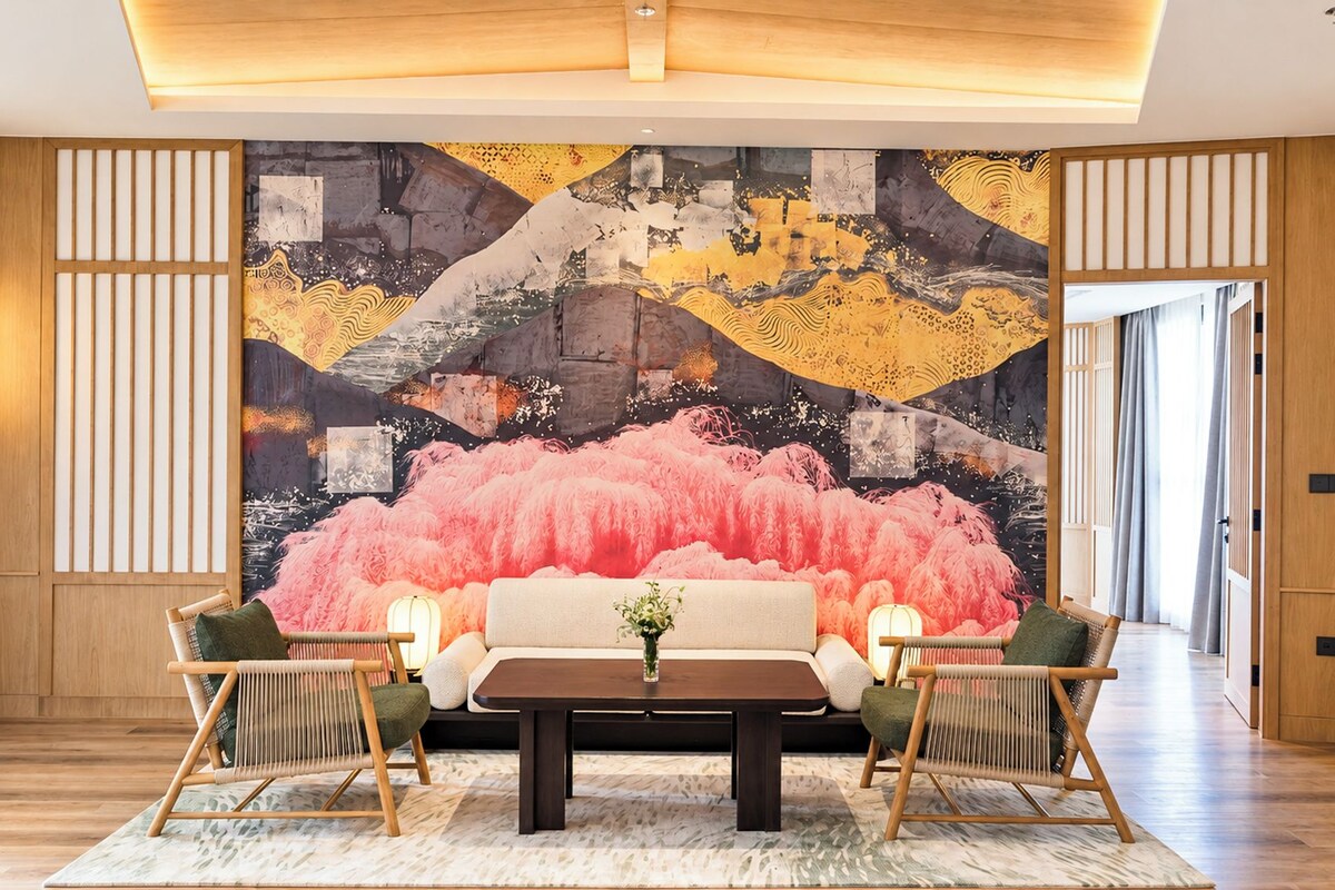 A room with a large abstract painting, a sofa, two chairs, a coffee table, and a vase with flowers.