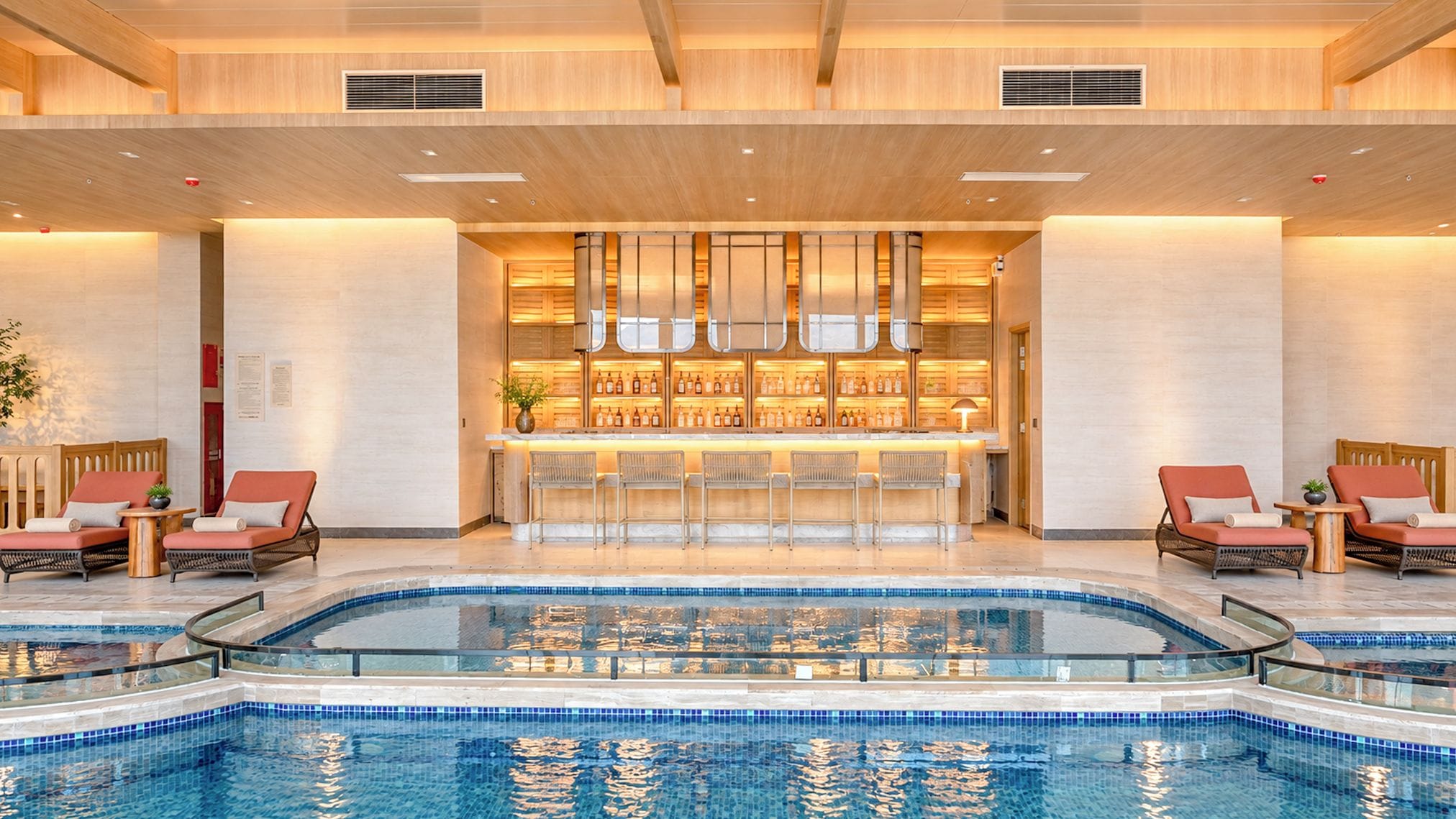 A hotel lobby with a pool, seating areas, and a bar.