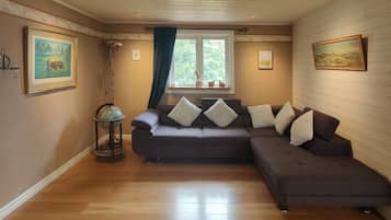 A cozy living room with a brown sofa, a globe on a stand, and artwork on the walls.