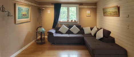 A cozy living room with a brown sofa, a globe on a stand, and artwork on the walls.
