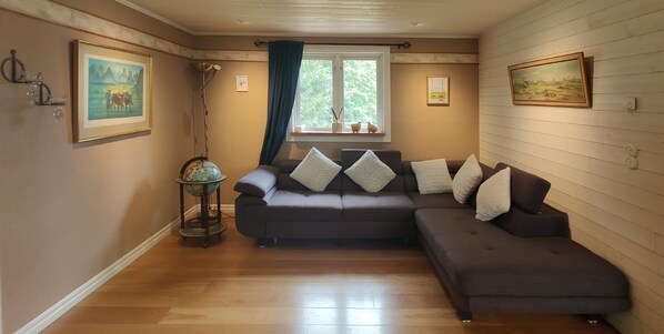 A cozy living room with a brown sofa, a globe on a stand, and artwork on the walls.