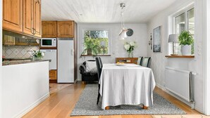 Una cocina compacta con armarios de madera, una mesa de comedor con mantel blanco y una silla negra.
