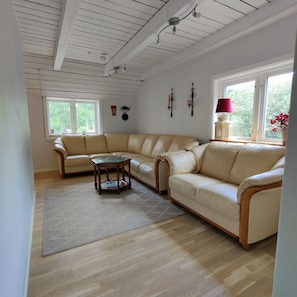 Een woonkamer met een beige modulaire bank, een houten salontafel en een kamerbreed tapijt.