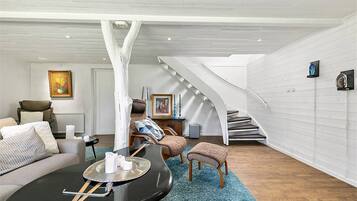 Un amplio salón con techo alto, una escalera y una zona de estar acogedora.