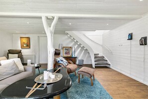 A spacious living area with a high ceiling, a staircase, and a cozy seating arrangement. - Hazelnut Villa - Lake & Town Retreat (Osby)