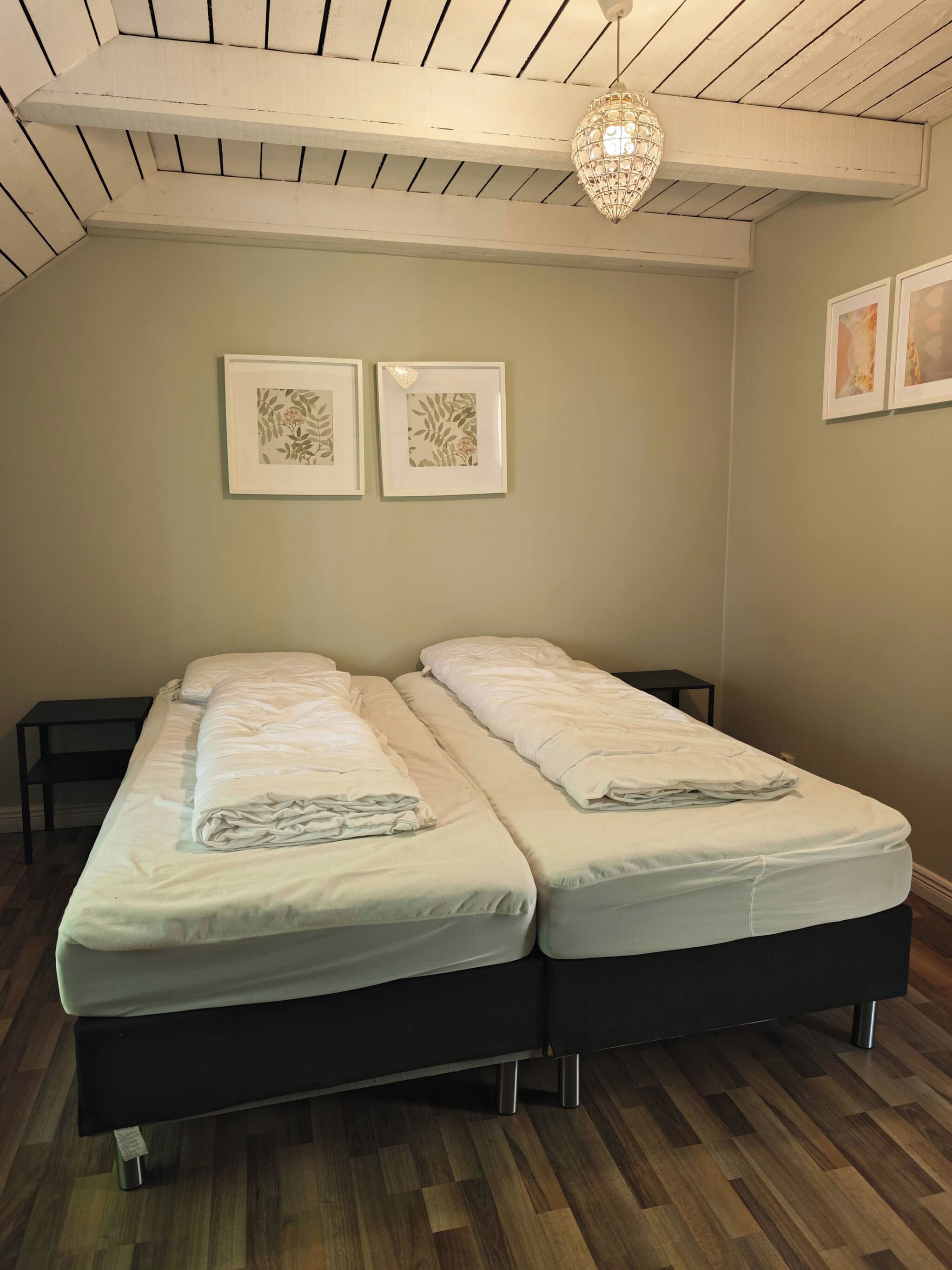 Una habitación con dos camas, techo de madera y una lámpara colgante.