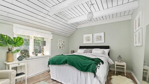 Un dormitorio con cama, ventana, mesita de noche y tocador.