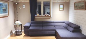 Una sala de estar en esquina con un sofá modular, una lámpara globo y un ventanal con vistas al exterior.