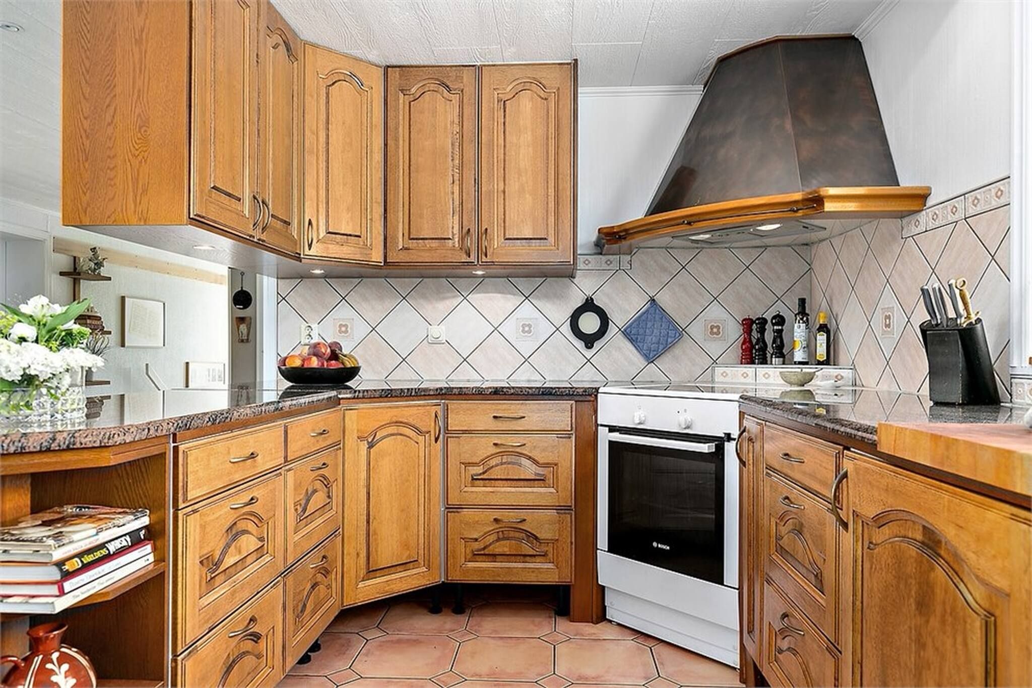Una cocina con armarios de madera, un horno Bosch y un salpicadero de azulejos.